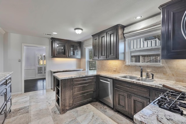 kitchen with stainless steel dishwasher, a healthy amount of sunlight, a sink, and tasteful backsplash