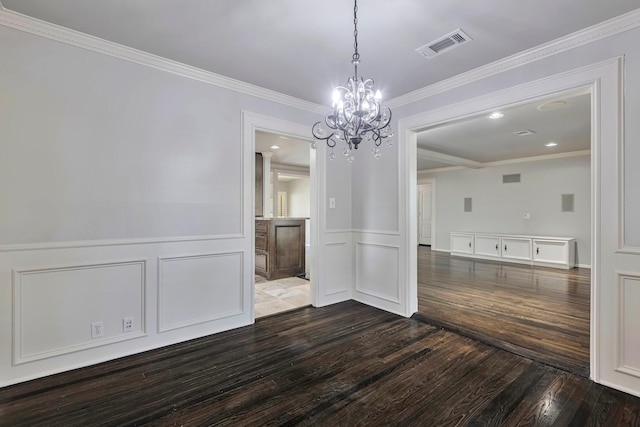 unfurnished dining area with a wainscoted wall, visible vents, an inviting chandelier, and dark wood-type flooring