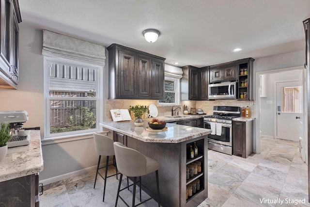 kitchen with open shelves, baseboards, tasteful backsplash, a sink, and appliances with stainless steel finishes