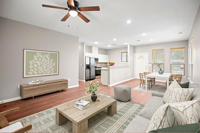 living room with light wood-style flooring, ceiling fan, baseboards, and recessed lighting