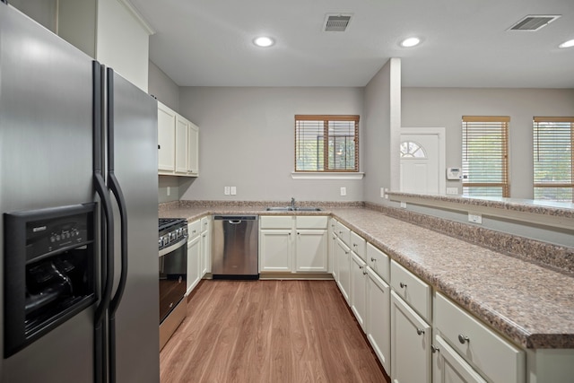 kitchen with light wood-style flooring, a sink, visible vents, and stainless steel appliances