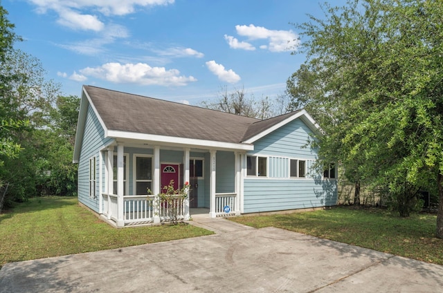 ranch-style home with roof with shingles, covered porch, and a front yard
