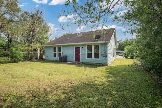 back of property with a yard and central AC