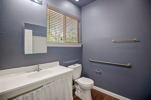 bathroom featuring vanity, baseboards, a textured wall, toilet, and wood finished floors
