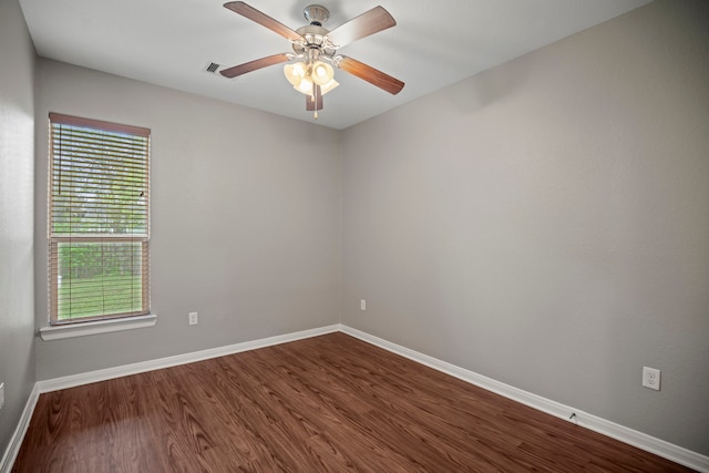 empty room with visible vents, baseboards, a ceiling fan, and dark wood finished floors