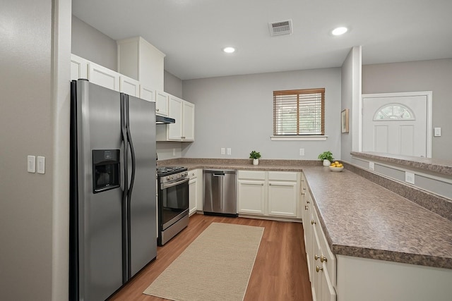 5215 Kingsbury St, Houston, TX 77021 - kitchen with stainless steel appliances, wood finished floors, white cabinetry, recessed lighting, and a peninsula