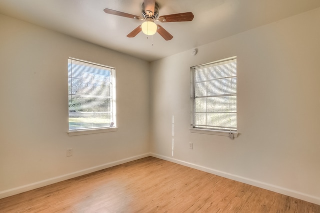 spare room with a wealth of natural light, light wood-type flooring, baseboards, and a ceiling fan