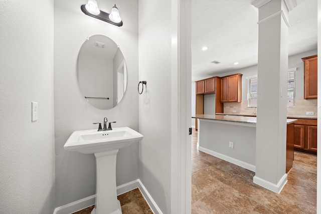 bathroom featuring a sink, decorative backsplash, baseboards, and recessed lighting