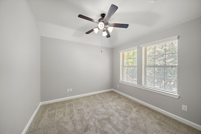 carpeted spare room featuring ceiling fan and baseboards