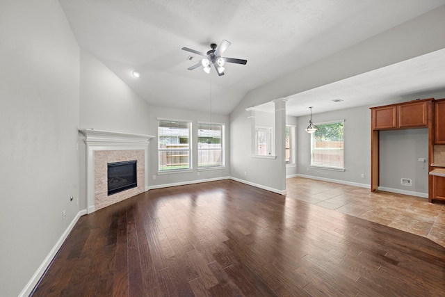 unfurnished living room with ceiling fan, wood finished floors, plenty of natural light, and a glass covered fireplace