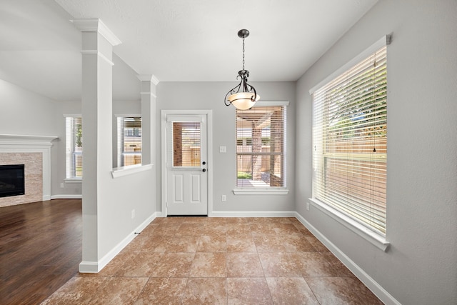 foyer entrance with decorative columns, baseboards, and a glass covered fireplace