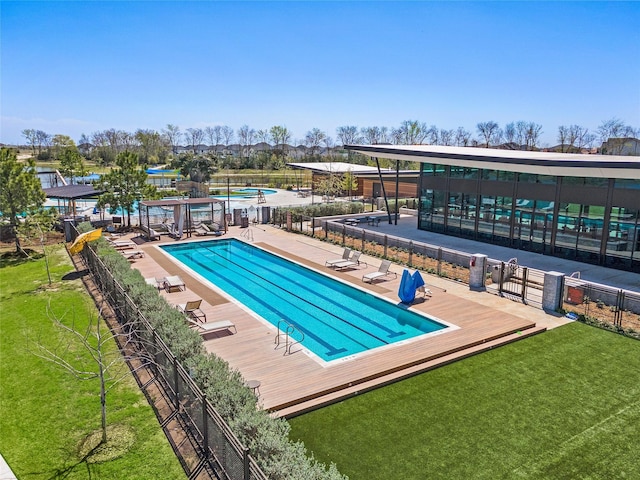 pool featuring fence, a patio, and a lawn