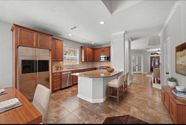 kitchen with a kitchen breakfast bar, recessed lighting, visible vents, brown cabinetry, and stainless steel appliances
