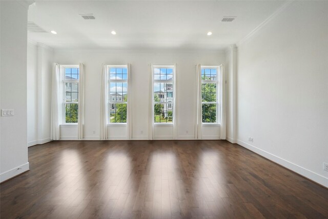 unfurnished room featuring baseboards, visible vents, ornamental molding, and dark wood-type flooring