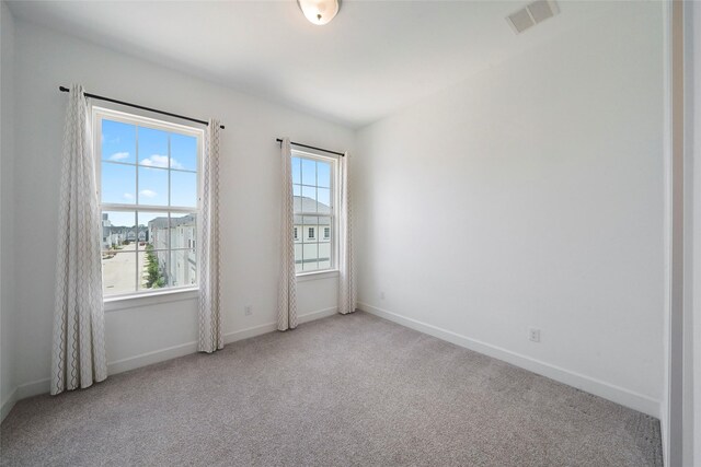 unfurnished room with light colored carpet, visible vents, and baseboards