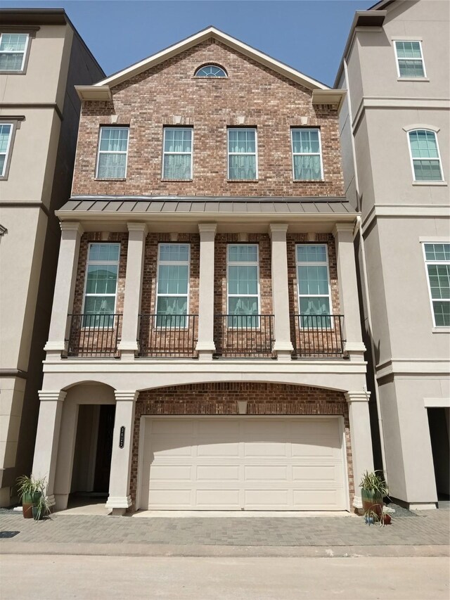 multi unit property with driveway, a standing seam roof, brick siding, and an attached garage