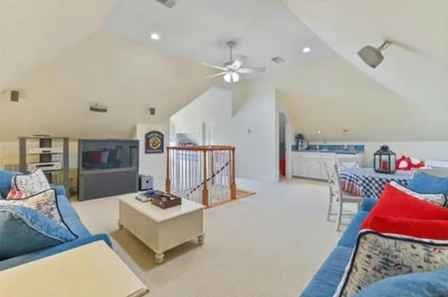 carpeted living room with a ceiling fan and vaulted ceiling