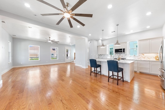 13 Caravelle Ct, Galveston, TX 77554 - kitchen featuring appliances with stainless steel finishes, ceiling fan, a center island, decorative backsplash, and white cabinetry