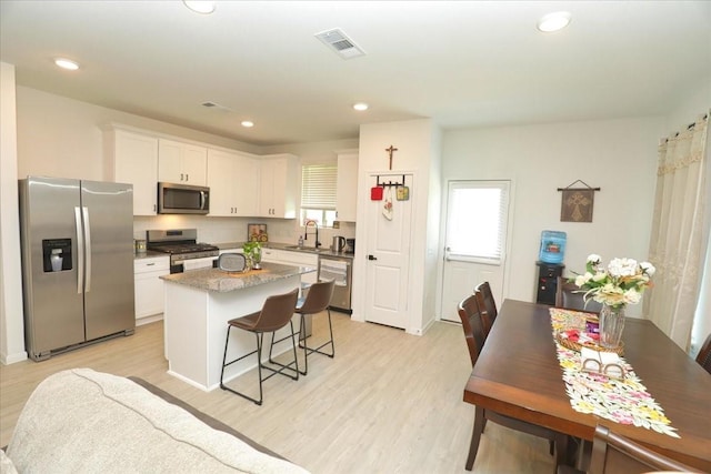 17014 Wild Stream Ct, Conroe, TX 77302 - kitchen with a sink, stainless steel appliances, light wood-type flooring, visible vents, and a kitchen island