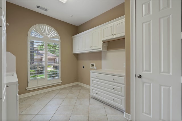 8802 Kennet Valley Rd, Spring, TX 77379 - washroom with hookup for an electric dryer, cabinet space, washer hookup, light tile patterned floors, and baseboards