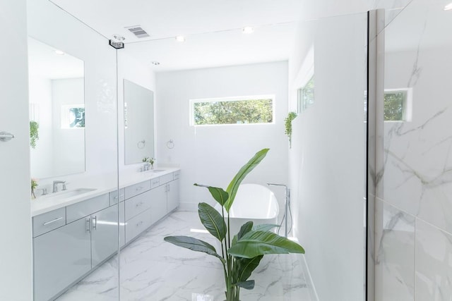 bathroom with a soaking tub, a sink, double vanity, visible vents, and marble finish floor