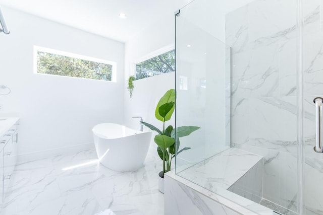bathroom featuring marble finish floor, vanity, a marble finish shower, baseboards, and a freestanding tub