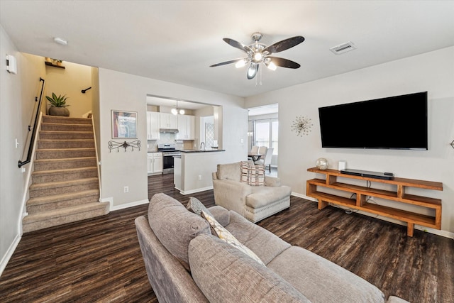 living area featuring baseboards, ceiling fan, dark wood-style flooring, and stairs