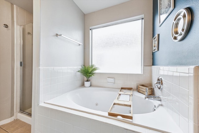 full bathroom featuring a tub with jets, a shower stall, and tile patterned flooring