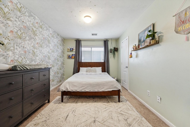 bedroom with wallpapered walls, visible vents, light carpet, and baseboards