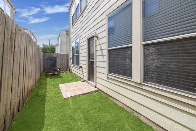 view of side of home featuring a fenced backyard, a lawn, and cooling unit