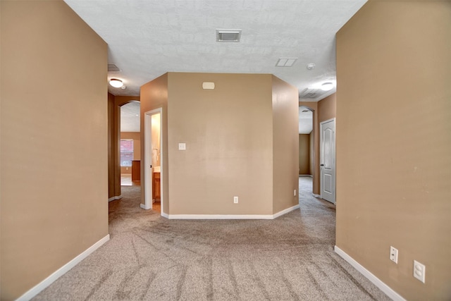 carpeted spare room featuring visible vents and baseboards