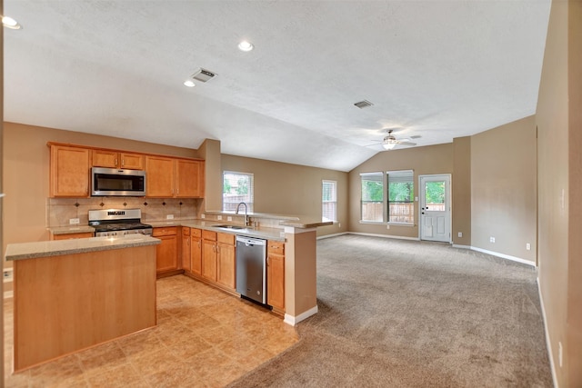kitchen with appliances with stainless steel finishes, a sink, a peninsula, open floor plan, and visible vents