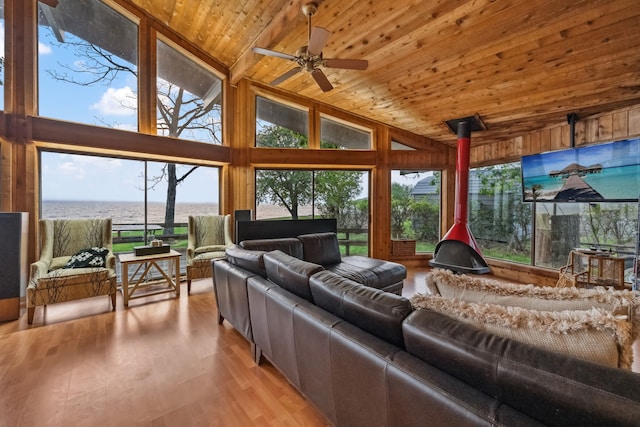 living area with ceiling fan, high vaulted ceiling, wood ceiling, wood finished floors, and wooden walls