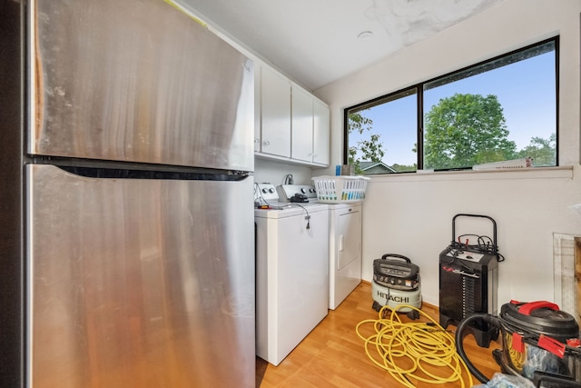 laundry room with independent washer and dryer, cabinet space, and light wood-style flooring