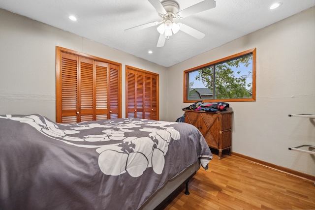 bedroom featuring baseboards, recessed lighting, multiple closets, ceiling fan, and wood finished floors