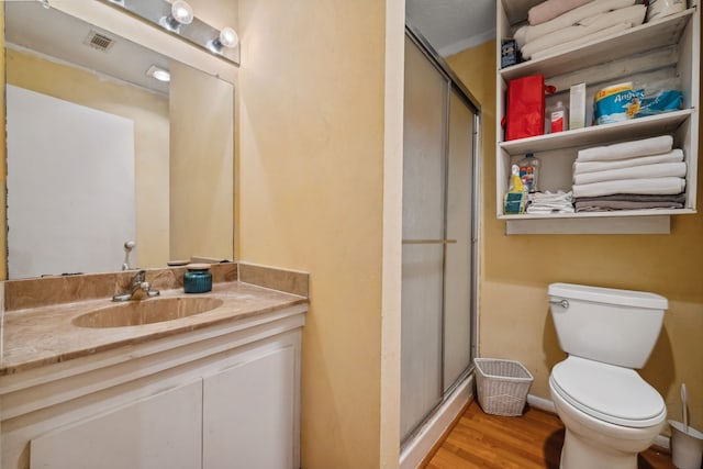 full bathroom with a shower stall, vanity, visible vents, toilet, and wood finished floors