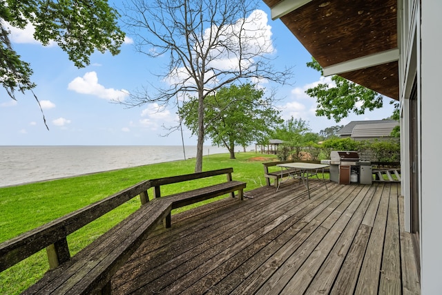 wooden deck with a grill, a water view, and a lawn