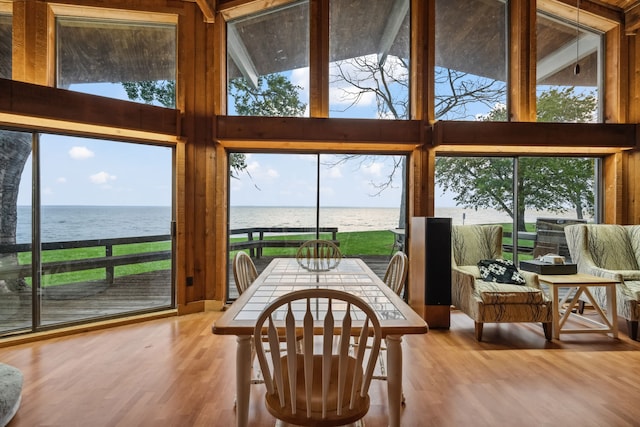 dining area featuring a water view, a high ceiling, and wood finished floors