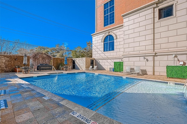 pool with a patio and fence
