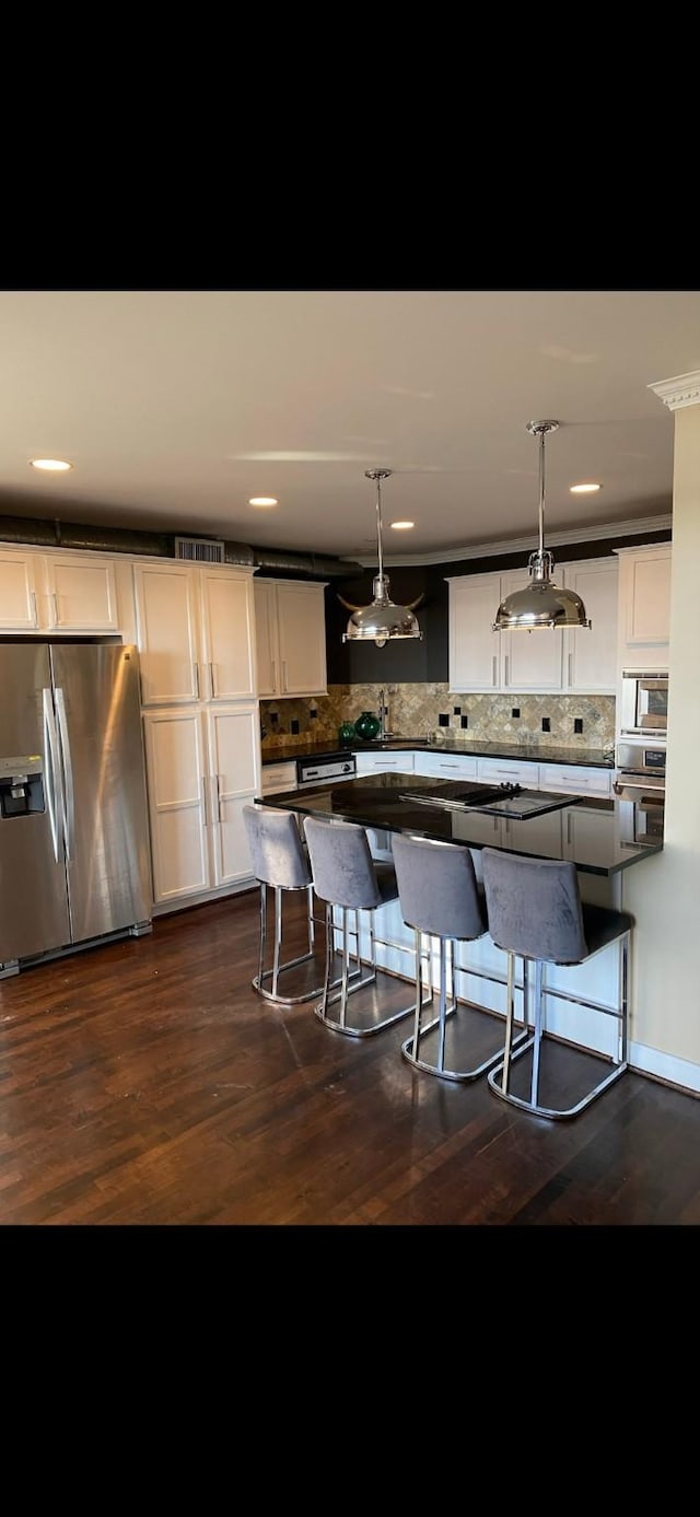 kitchen with stainless steel refrigerator with ice dispenser, decorative light fixtures, and tasteful backsplash