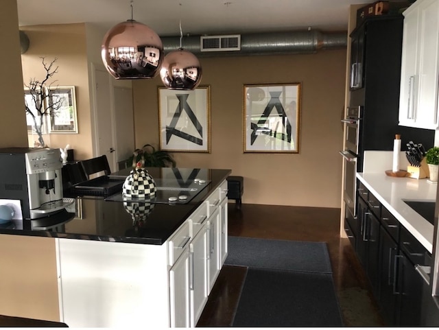 kitchen featuring dark countertops, white cabinetry, and visible vents