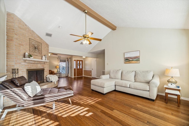 living room featuring beamed ceiling, visible vents, ceiling fan, hardwood / wood-style floors, and a brick fireplace