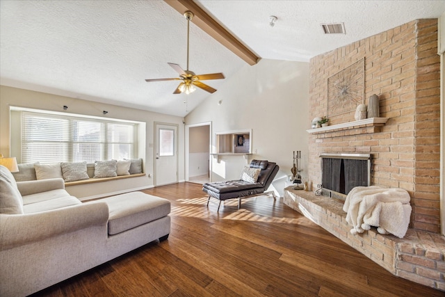living area with lofted ceiling with beams, ceiling fan, wood-type flooring, visible vents, and a textured ceiling