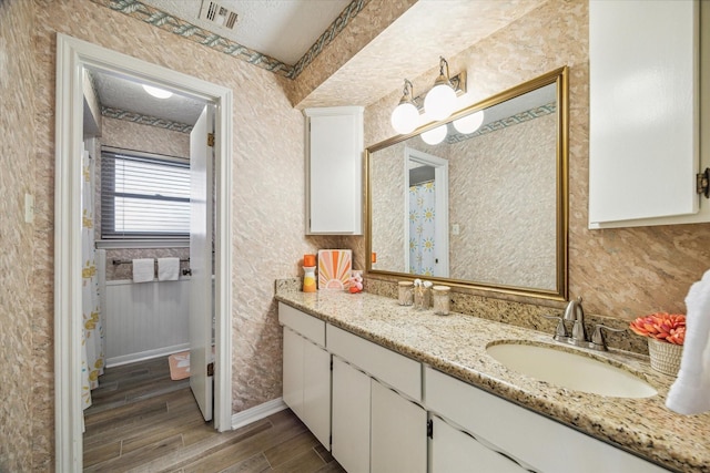 bathroom with wood finished floors, visible vents, vanity, and a textured ceiling