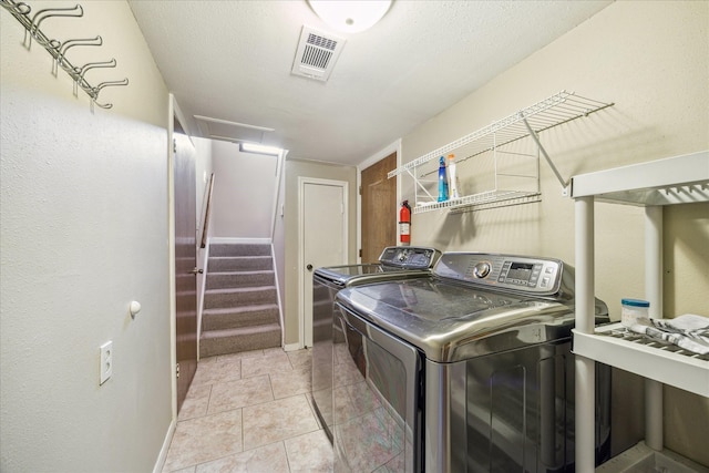laundry room featuring light tile patterned floors, washer and dryer, visible vents, and baseboards