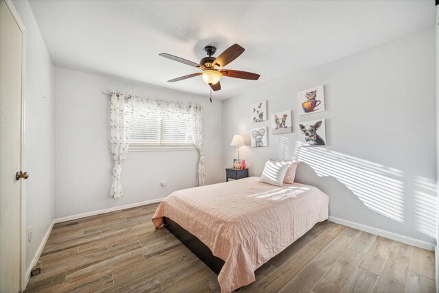 bedroom featuring ceiling fan, wood finished floors, and baseboards