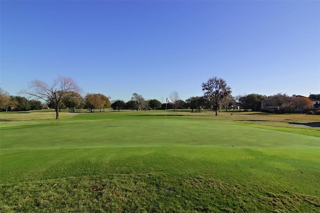 view of property's community with golf course view and a lawn