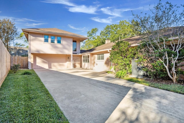 view of front facade featuring fence, driveway, a front yard, and an attached garage