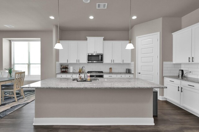 17052 Easter Lily Dr, Conroe, TX 77385 - kitchen featuring stainless steel microwave, stove, a sink, tasteful backsplash, and light stone countertops