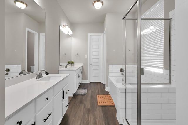 17052 Easter Lily Dr, Conroe, TX 77385 - full bathroom featuring two vanities, a shower stall, a bath, and wood finished floors